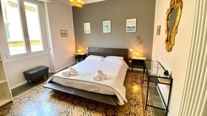 Une chambre à coucher moderne avec un grand lit, des tables de chevet et un sol à motifs.