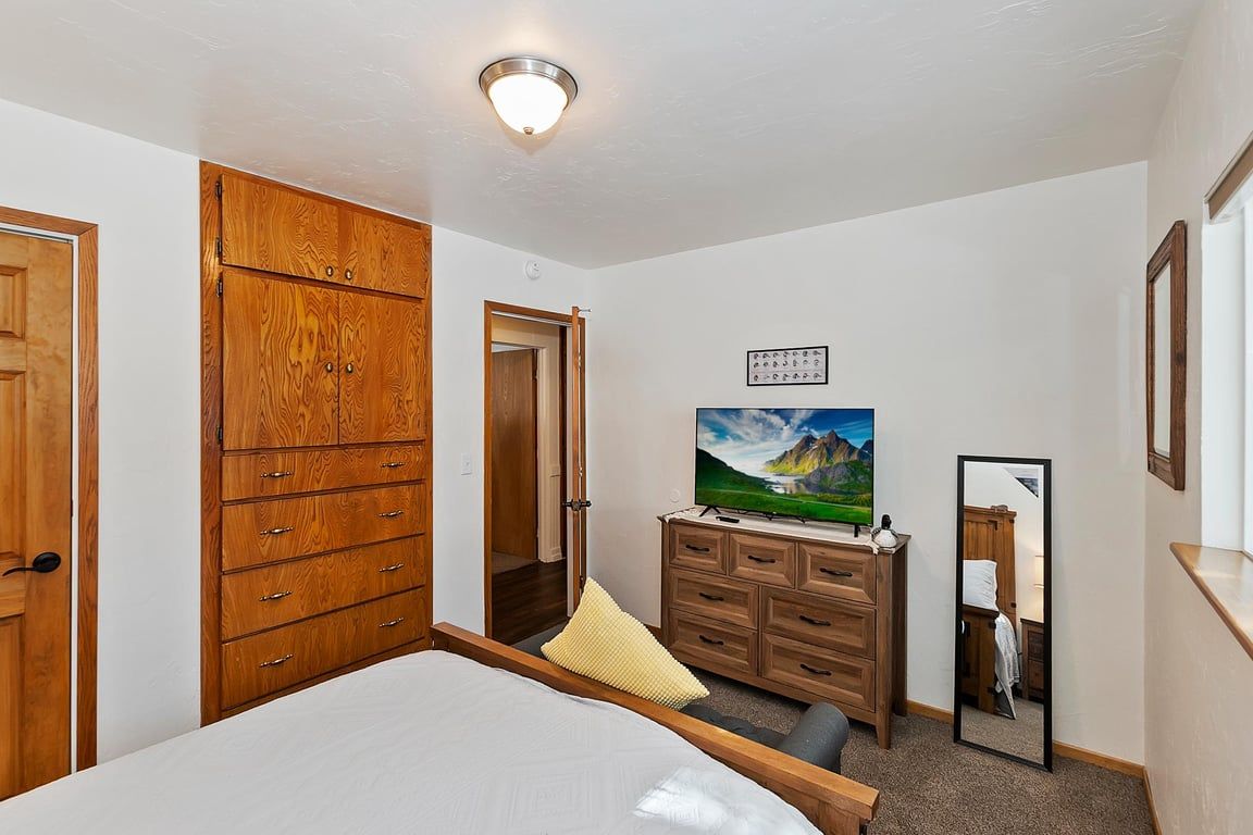 Ein Schlafzimmer mit Bett, Holzschrank, Schminktisch und Spiegel.