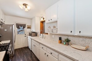 A kitchen with white cabinets, a stainless steel refrigerator, a microwave, and a gas stove. - PET FRIENDLY! Fully Fenced Yard! Close to the Convention Center! 2 Master Suites! (Big Bear City)