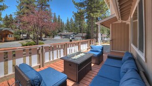 Una terraza con mobiliario exterior, una chimenea y vistas a una zona residencial con casas y árboles.