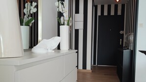 A modern room with a white dresser, two white vases with orchids, a mirror, and a wooden floor. - La Suite Appartement Avec Terrasse Proche Plages Tout a Pied (Concarneau)