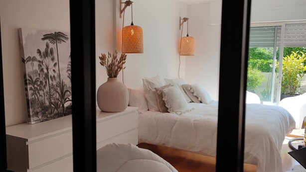 A bedroom with a large window, a bed with white bedding, a bedside table with a vase, and two hanging lamps. - La Suite Appartement Avec Terrasse Proche Plages Tout a Pied (Concarneau)
