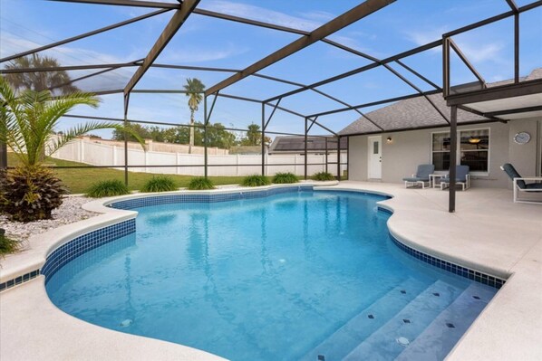 Relax by the pool surrounded by a covered patio with a seating area and steps leading into the water.
