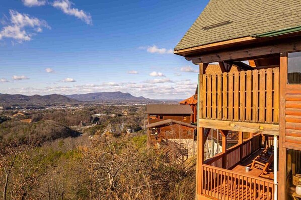 A wooden cabin with a balcony overlooking a mountainous landscape.