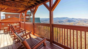 Une terrasse en bois avec des bancs, offrant une vue sur un paysage montagneux.