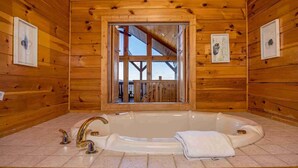 Une cabane en bois dotée d’une grande baignoire, de fenêtres à cadre et d’œuvres d’art encadrées accrochées aux murs.