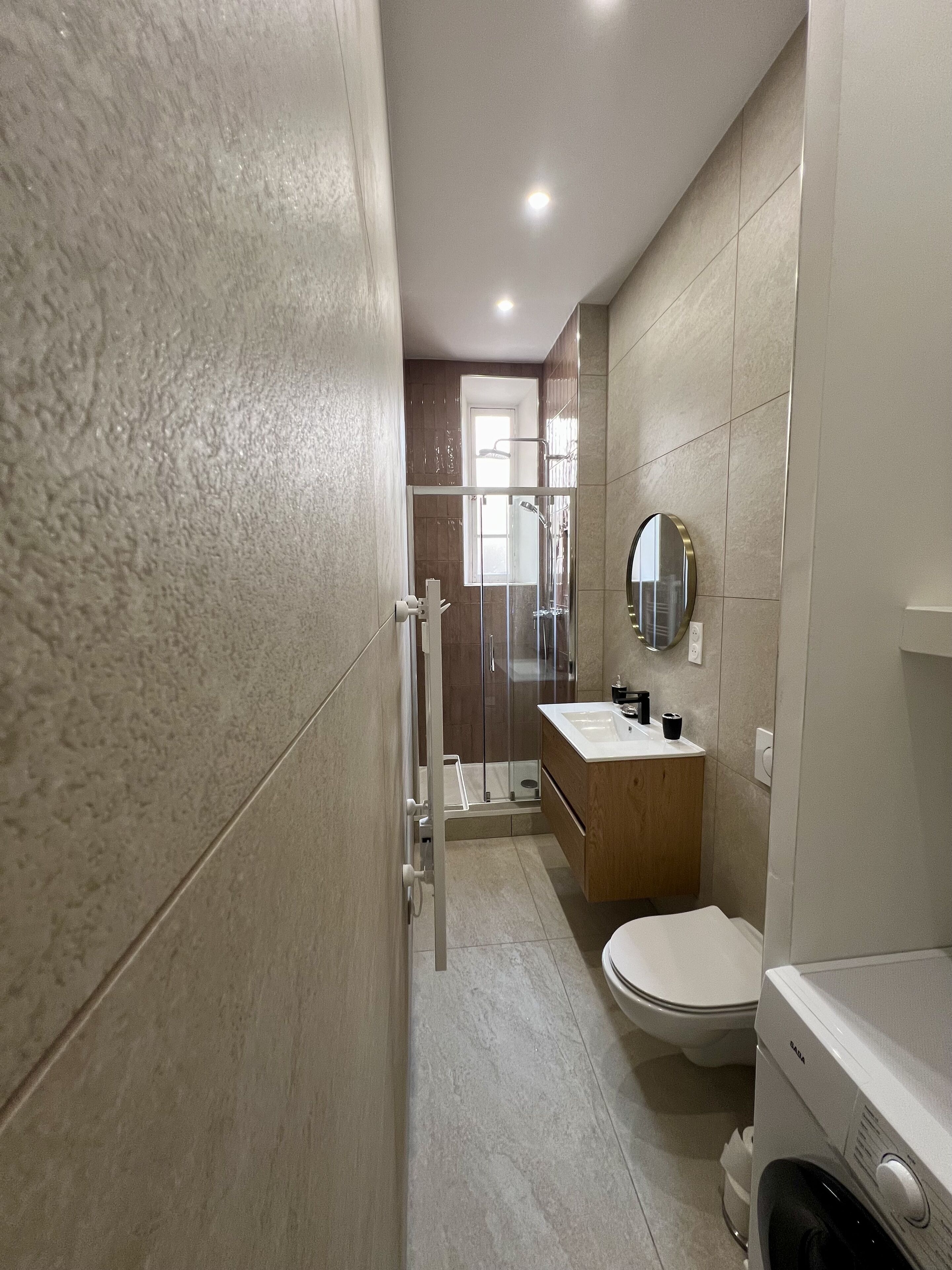 A modern bathroom with a shower, toilet, and sink.