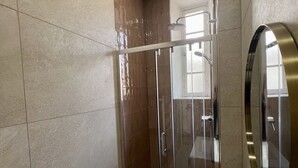 Ein modernes Badezimmer mit einer gläsernen Duschkabine, einem weißen Waschbecken und einem großen Spiegel.