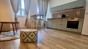 Eine moderne Küche mit Holzboden, einem Essbereich mit Tisch und Stühlen sowie einem kleinen Hocker.