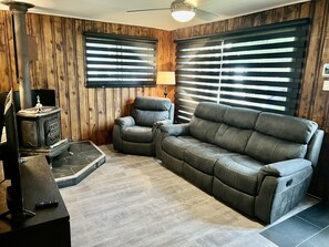 A cozy living room with a sectional sofa, a fireplace, and wooden paneled walls.