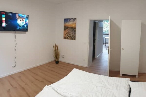 A bedroom with a bed, a TV mounted on the wall, a painting, and a door leading to another room. - Atelierwohnung in Ruhrgebiet (Mülheim an der Ruhr)