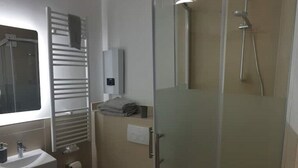 Een moderne badkamer met een douchecabine van glas, een handdoekhouder en een wastafel.
