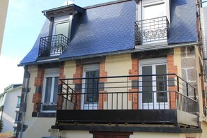 A two-story building with a blue tiled roof, brick and stone facade, and black metal balconies. - Villa Primevere N°3 (Mont-Dore)