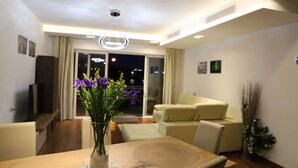 Una sala moderna con una mesa de comedor, un televisor y un jarrón de flores.