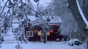 Een huis bedekt met sneeuw, met een rode gevel, een duidelijke deur en een raam versierd met een ster.