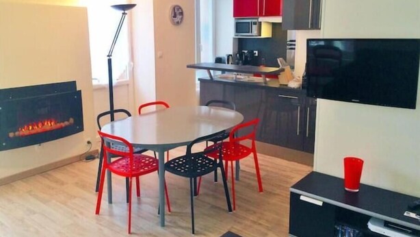 A modern kitchen with red cabinets, a microwave, and a flat-screen TV.