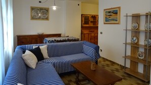 Ein Wohnzimmer mit einem gestreiften Sofa, einem Holztisch und einem Regal mit dekorativen Tellern.