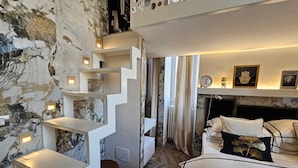 Een moderne slaapkamer met een marmeren wand, een witte trap, een bed met witte lakens en een klein nachtkastje.