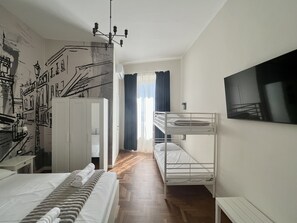 Ein Zimmer mit einem Etagenbett, einem Schreibtisch, einem Kleiderschrank und einem Wandbild.