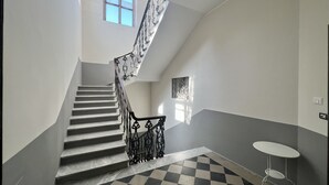 A staircase with a checkered floor, a white table, and a small window. - Fuori dal Porto2-Quadrupla VistaMare byBeYourHome (Civitavecchia)
