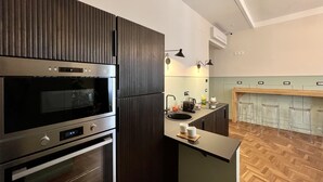 A modern kitchen with dark wood cabinets, stainless steel appliances, a wooden countertop, and a herringbone-patterned floor. - Fuori dal Porto2-Quadrupla VistaMare byBeYourHome (Civitavecchia)