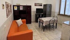 A compact living space with a sofa, a dining table with chairs, a TV, a refrigerator, and a cabinet. - Casa Vacanze Il Conservatorio - by Be Your Home (Civitavecchia)