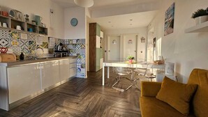 Een moderne keuken met een visgraat houten vloer, witte kasten en een kleurrijke achterwand.