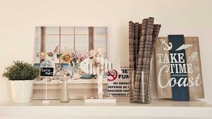 Een plank met diverse decoratieve objecten, waaronder een bordje met de tekst 'TAKE TIME TO COAST'.