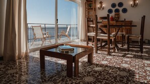 A spacious room with a large window, a wooden table, and a balcony with chairs. - Holiday Apartment by the sea by Be Your Home (Santa Marinella)