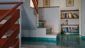 A staircase with wooden railings leading to a landing with a bookshelf and framed pictures on the wall. - Holiday Apartment by the sea by Be Your Home (Santa Marinella)