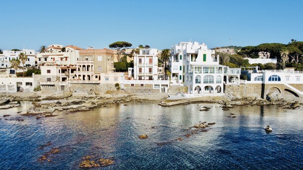A coastal town with white buildings, a stone bridge, and clear blue water. - Holiday Apartment by the sea by Be Your Home (Santa Marinella)