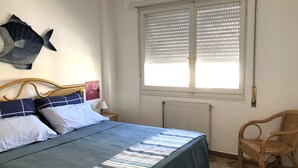 A bedroom with a bed, a window with blinds, a radiator, and a chair. - Casa Raffaello - by Be Your Home (Santa Marinella)