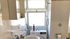 A compact bathroom with a sink, a washing machine, and a toilet. - Casa Raffaello - by Be Your Home (Santa Marinella)