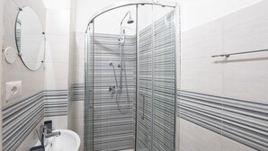 A modern bathroom with a glass-enclosed shower, a sink with a soap dish, and striped wall tiles. - Mazzini 144 -Stanza 1(Bagno Esterno) byBeYourHome (Rome)