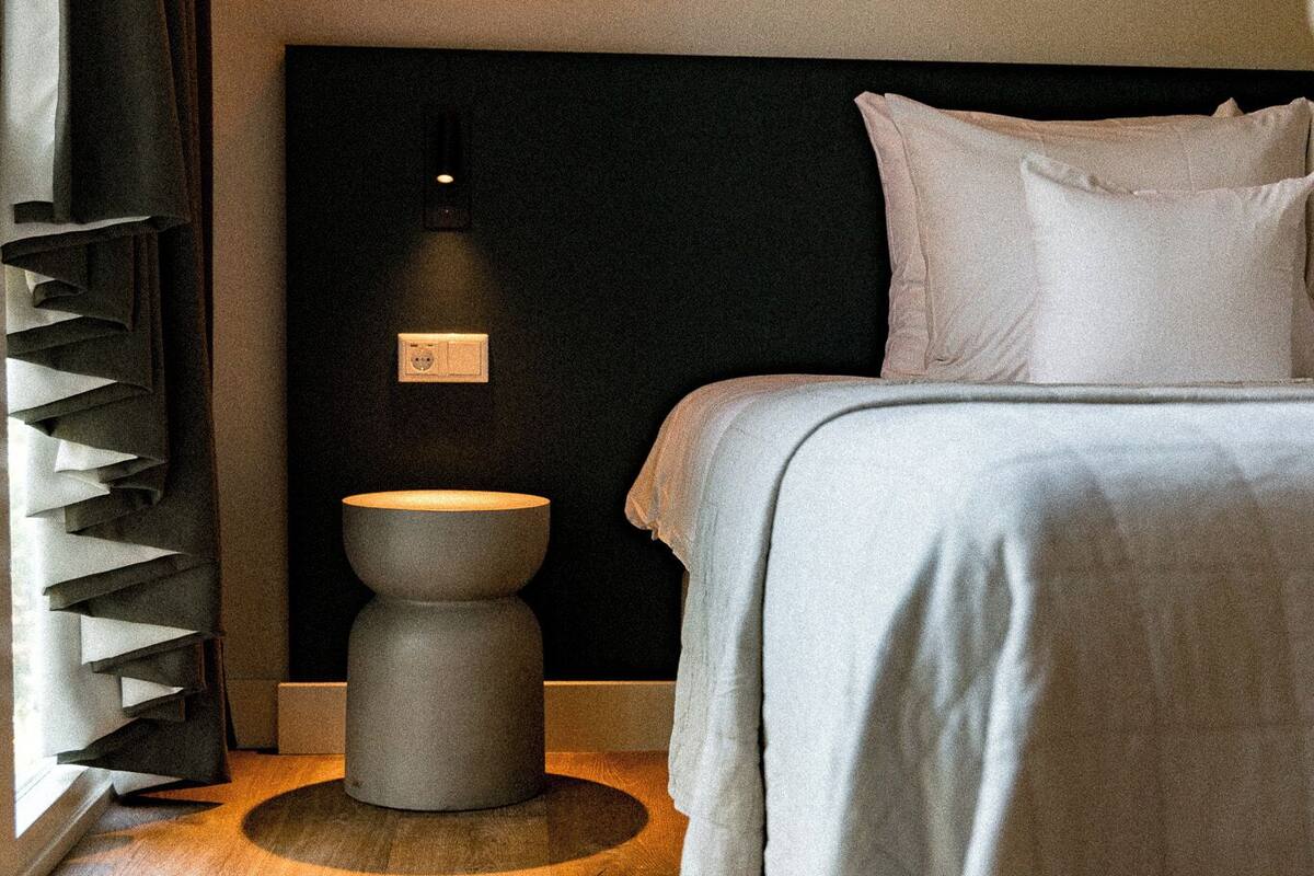 Ein modernes Hotelzimmer mit Bett, Nachttisch und Wandleuchte.