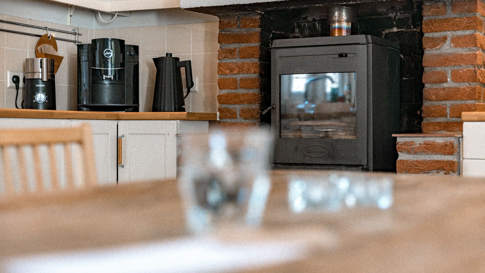 Una cocina con pared de ladrillo, cafetera, hervidor y estufa.