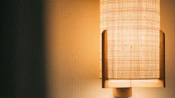 Une lampe murale dotée d’un abat-jour en tissu tressé.