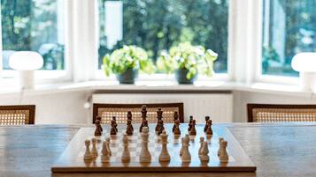 A chessboard on a table with a view of greenery through large windows.