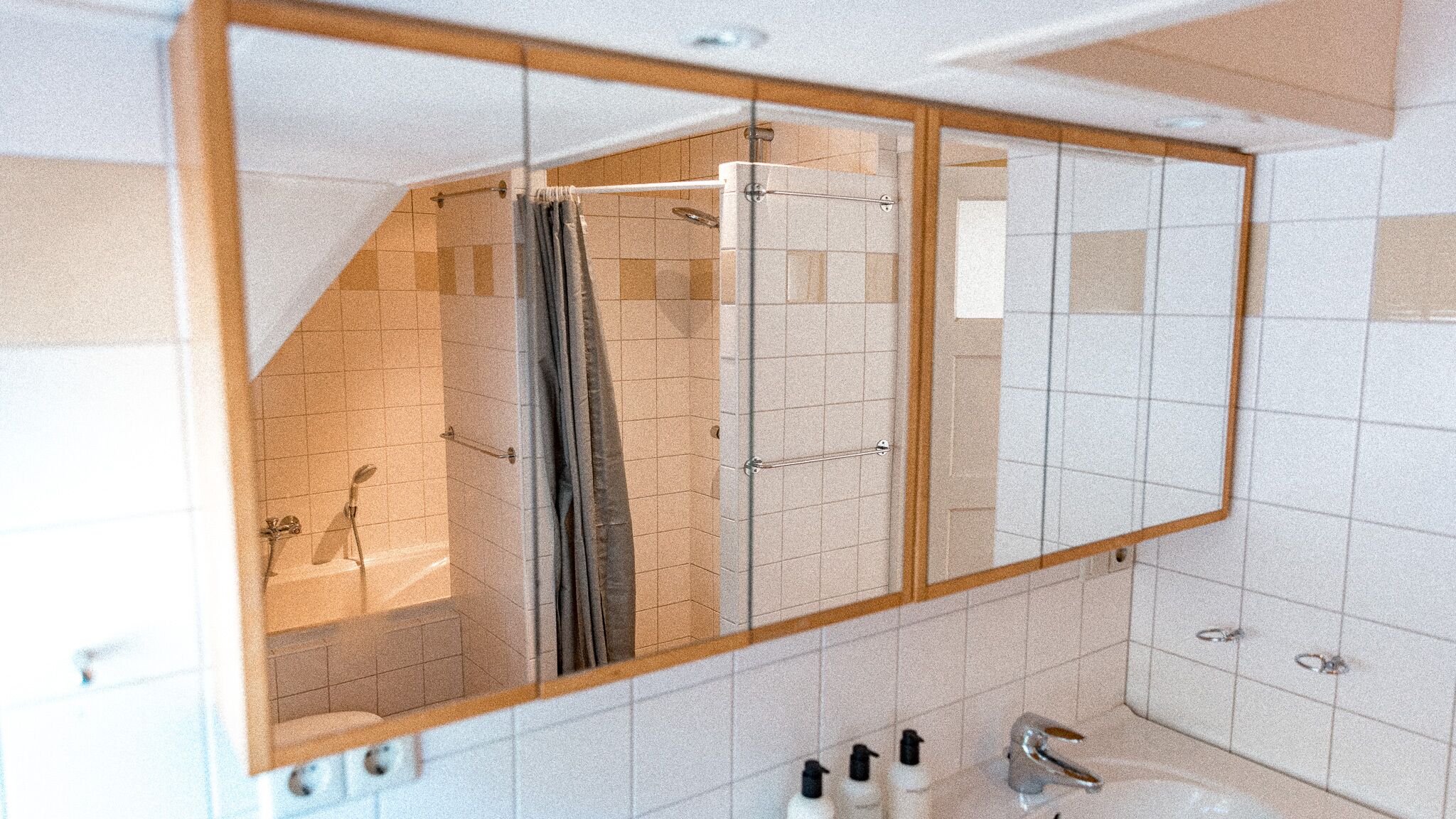 Un baño con un espejo grande, ducha e incluye artículos de aseo.