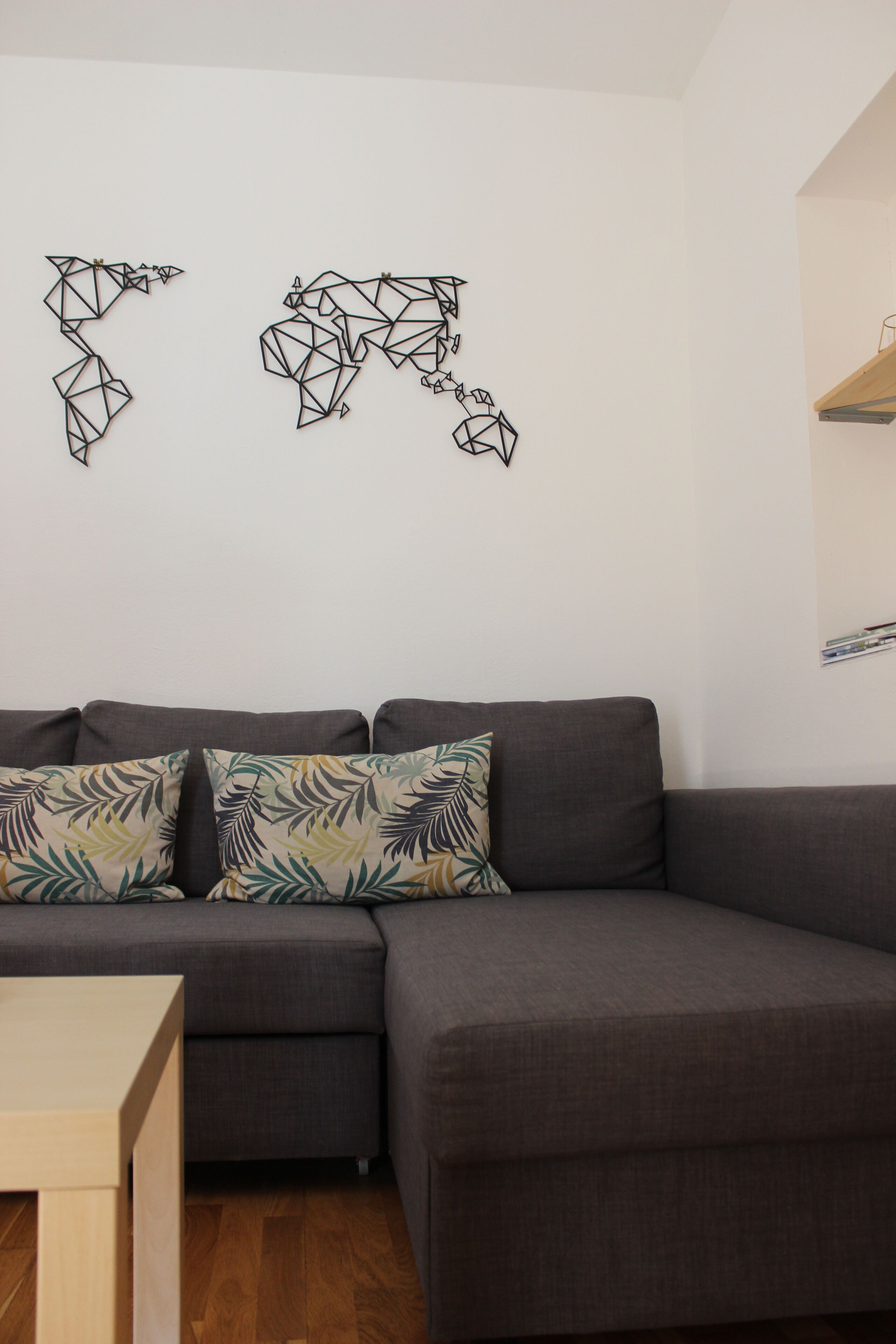 A modern living room with a dark grey sectional sofa, two patterned throw pillows, and a wooden coffee table.