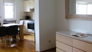 Una cocina moderna con armarios blancos, un comedor con mesa y sillas, y un espejo grande en la pared.