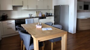 Una cocina moderna con armarios blancos, una mesa de comedor de madera y sillas grises.