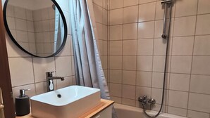 A bathroom with a sink, mirror, and shower.