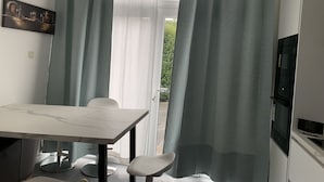 A modern dining area with a marble table, two chairs, and a television. - Appartement Séparé Avec Parking Gratuit (Vilvoorde)