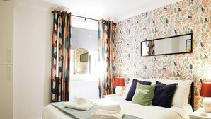 A hotel room with a bed, pillows, a nightstand, a lamp, and a mirror. - This apartment is a 2 bedroom(s), 2 bathrooms, located in Scarborough, North Yorkshire. (Scarborough)