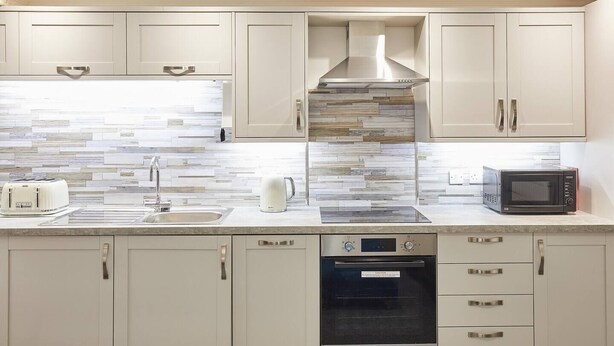 A modern kitchen with white cabinets, a stainless steel range hood, a built-in microwave, a toaster, and a dishwasher. - This apartment is a 2 bedroom(s), 2 bathrooms, located in Scarborough, North Yorkshire. (Scarborough)