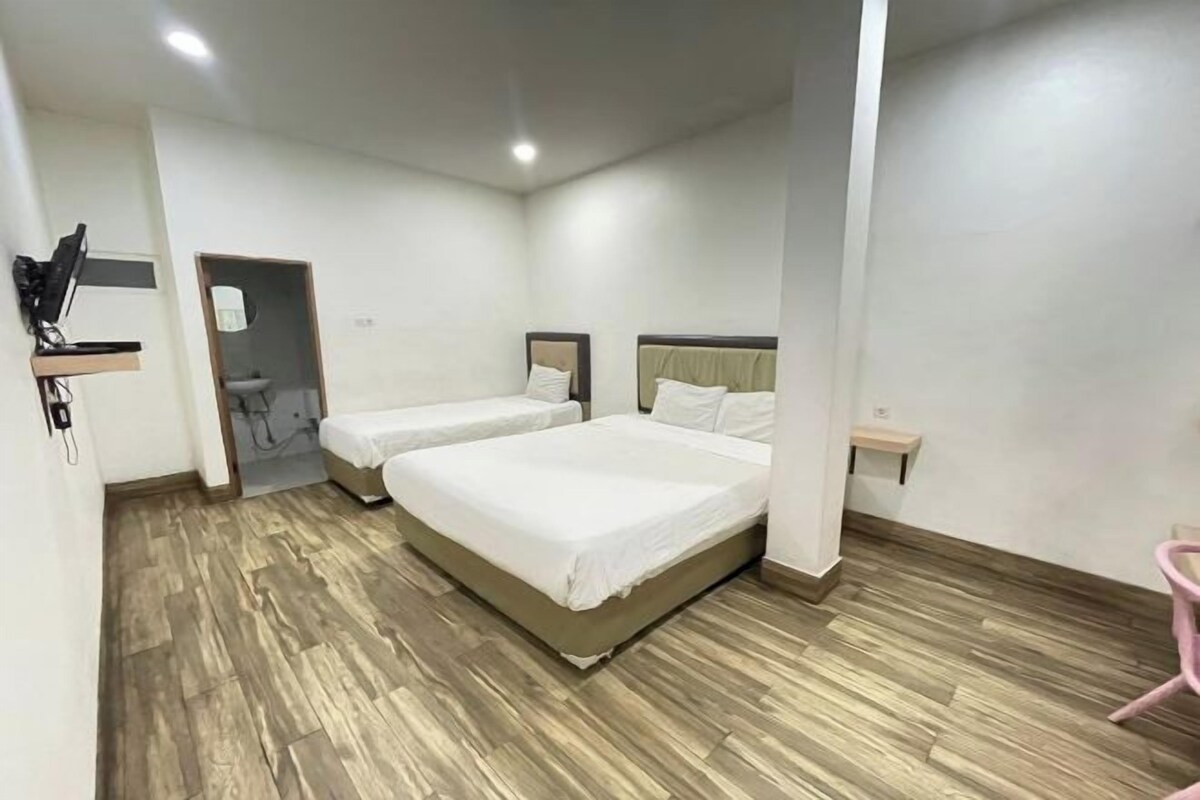 A hotel room with two beds, a wooden floor, a small desk, and a chair.