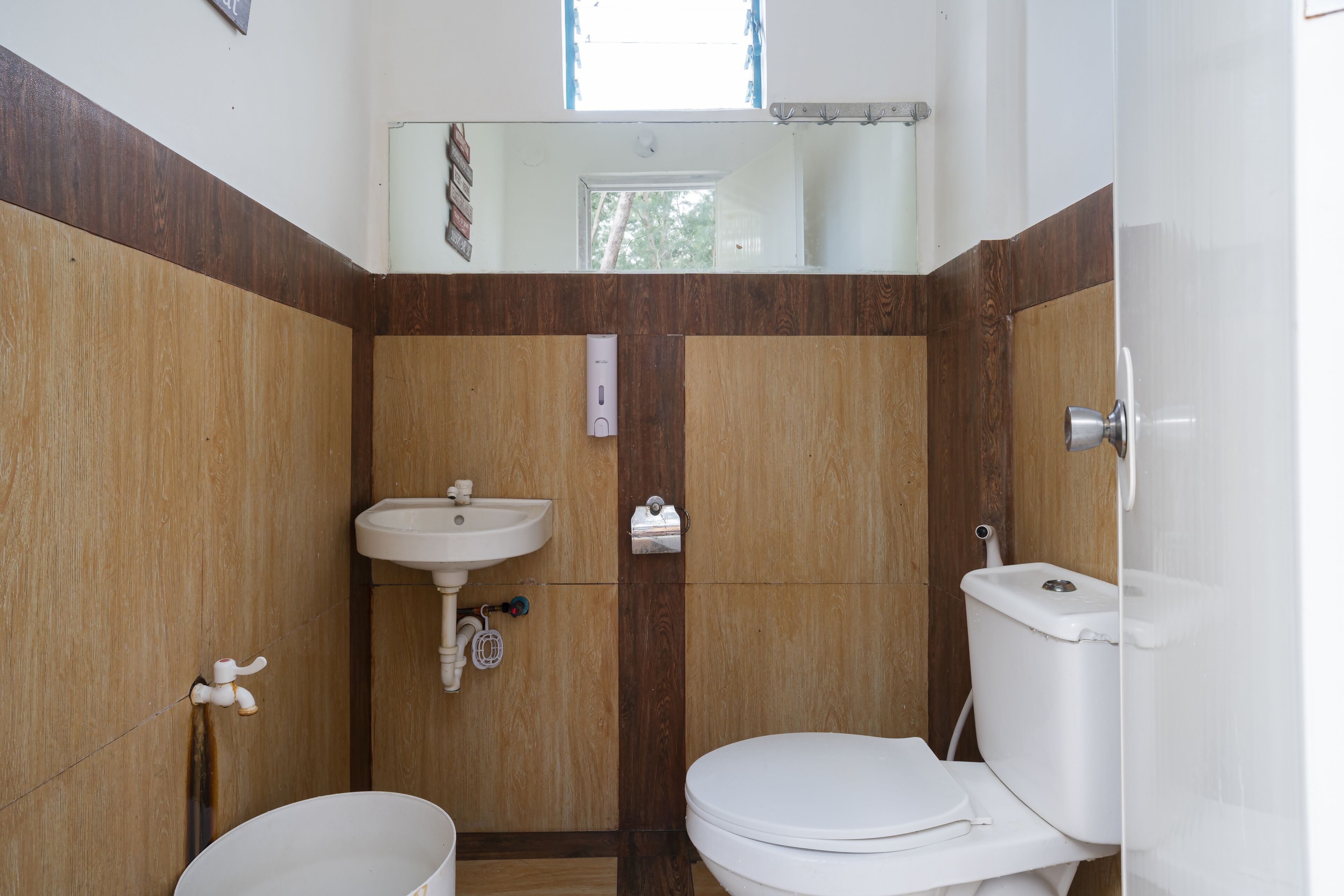 Un baño con tocador de madera, lavabo e inodoro.