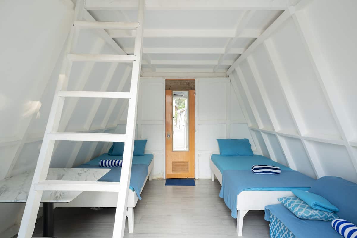 Habitación tipo dormitorio con dos camas, una escalera y una puerta que da a un espacio exterior.