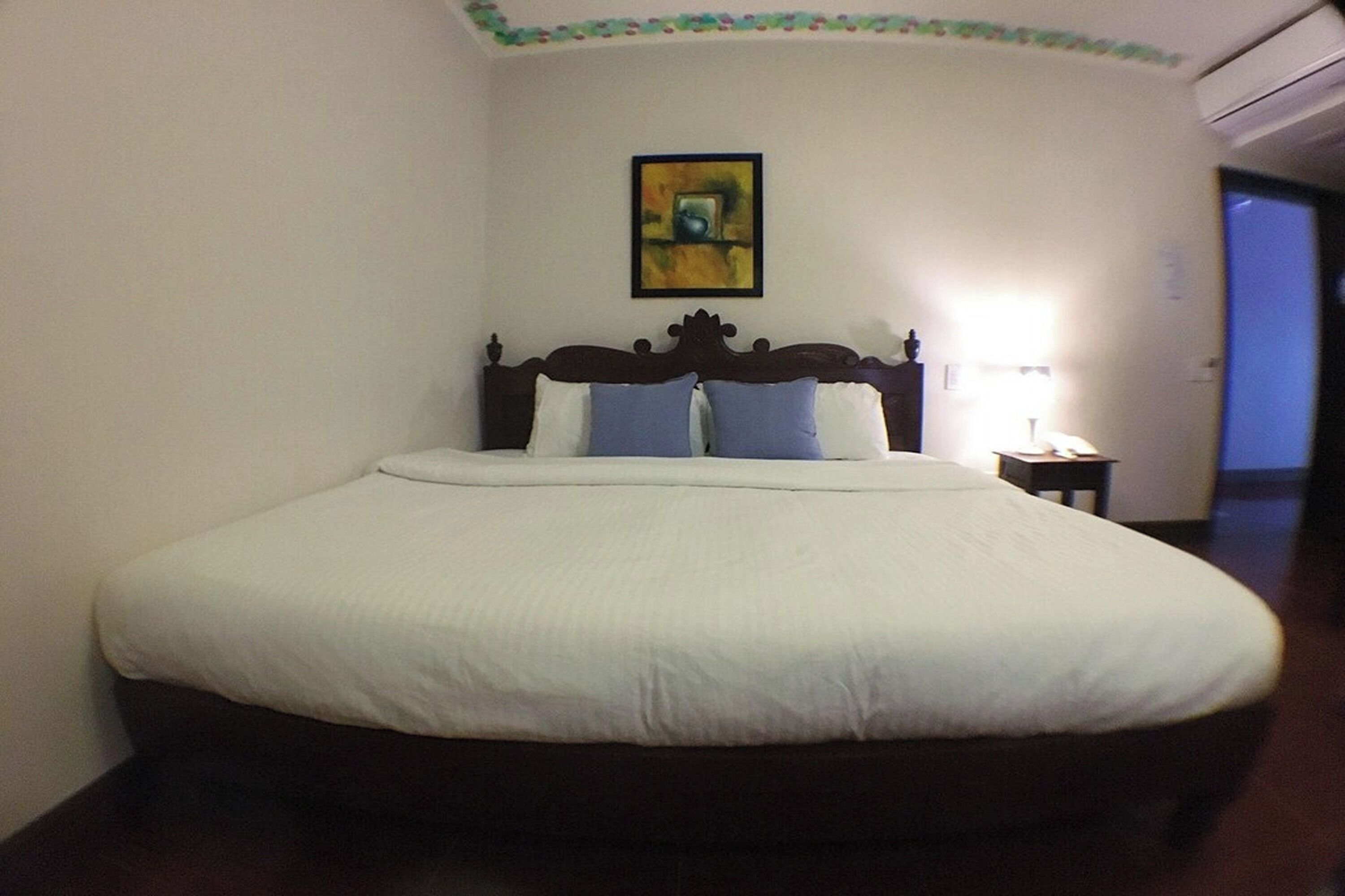 Una cama bien hecha con ropa blanca y dos almohadas azules en una habitación de hotel.